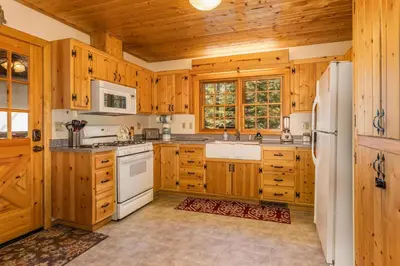 a kitchen with wooden cabinets and a white refrigerator at Place to Call Home - Cabin INSIDE Yosemite - Dog Friendly in South Wawona