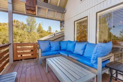 a blue couch sitting on a screened in porch at Stimboli Lodge- Sleeps 16 with tons of games and fun in Oakhurst