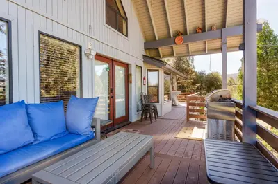 a porch with a blue couch on a house at Stimboli Lodge- Sleeps 16 with tons of games and fun in Oakhurst