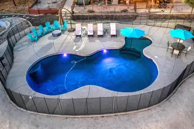 a large swimming pool with chairs and umbrellas at Mountain Elegance w/ pool, spa, projector in Coarsegold