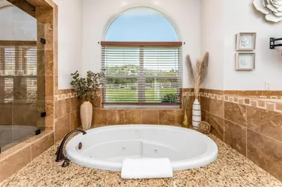 a large bathroom with a tub and a window at Mountain Elegance w/ pool, spa, projector in Coarsegold