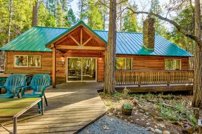 a cabin in the woods with chairs and a wooden porch at Peace of Mine - Cabin inside Yosemite - Dog Friendly in South Wawona