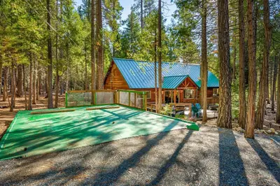 a log cabin in the woods with a green roof at Peace of Mine - Cabin inside Yosemite - Dog Friendly in South Wawona