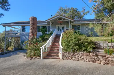 a house with a staircase leading to the front door at Doe Cabin Hot Tub/Playground/Game Room and more in Oakhurst