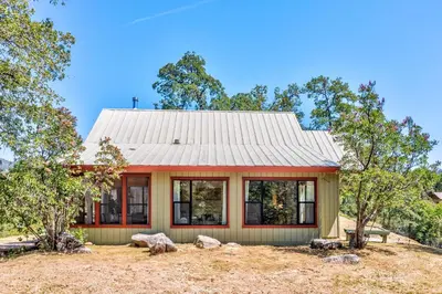 a house with a metal roof and windows at Hilltop Haven- Bright and Modern Cabin w/ hot tub and stunning views in Oakhurst