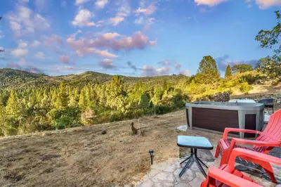 a patio with red chairs and a hot tub at Hilltop Haven- Bright and Modern Cabin w/ hot tub and stunning views in Oakhurst