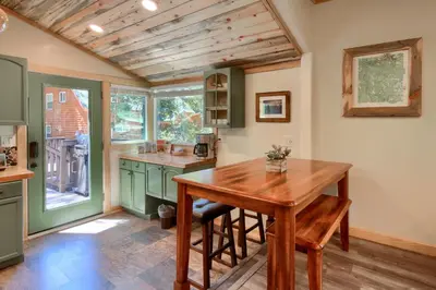 a kitchen with green cabinets and a wooden table at Beetlebark Bungalow- Inside Yosemite w/ hot tub EV charging cable in North Wawona