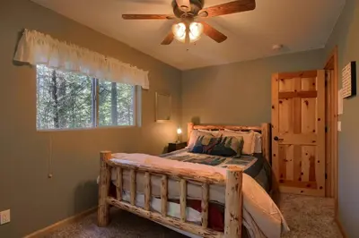 a bedroom with a bed with a ceiling fan and a window at Hibernation Hideaway- Inside Yosemite- Dog Friendly in South Wawona