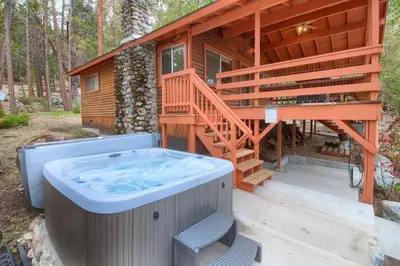 a house with a hot tub on a deck at Acorn Alley- inside Yosemite w/spa/firepit/sauna/EV in North Wawona