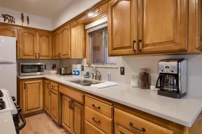 a kitchen with wooden cabinets and a white counter top at Acorn Alley- inside Yosemite w/spa/firepit/sauna/EV in North Wawona