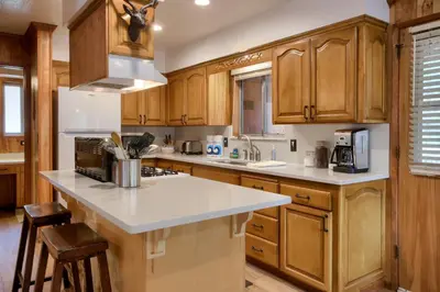 a kitchen with wooden cabinets and a white counter top at Acorn Alley- inside Yosemite w/spa/firepit/sauna/EV in North Wawona