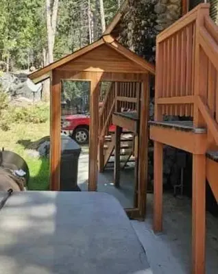 a small wooden house with a staircase in a yard at Acorn Alley- inside Yosemite w/spa/firepit/sauna/EV in North Wawona