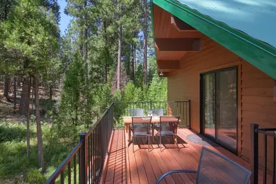 a deck with a table and chairs on a house at 3 Springs Hideout - Family cabin with hot tub in Yosemite in South Wawona