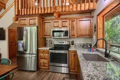 a kitchen with stainless steel appliances and wooden cabinets at 3 Springs Hideout - Family cabin with hot tub in Yosemite in South Wawona