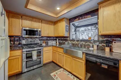 a kitchen with wooden cabinets and stainless steel appliances at Tahoe Donner Greenbelt Retreat in Truckee