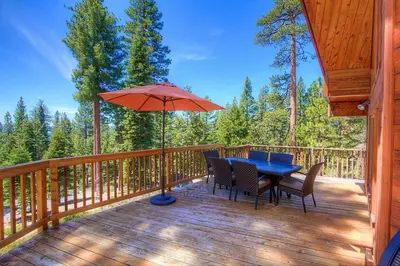a table and chairs on a deck with an umbrella at The Bass Chalet home in Kings Beach