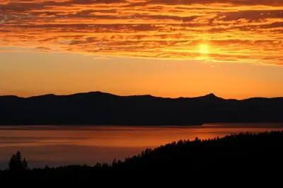 a sunset over a body of water with mountains at Lakescape condo in Stateline