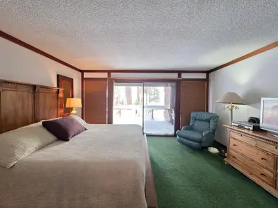 a bedroom with a bed and a chair and a television at Brockway Beachside Bungalo home in Kings Beach