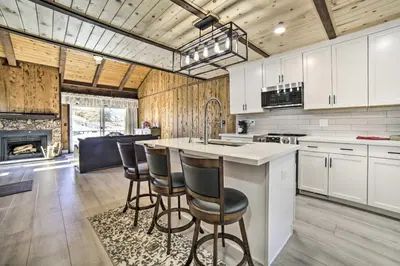 a kitchen with white cabinets and a counter with bar stools at 1 Mi to Lake Tahoe Vacation Rental Home! in Stateline
