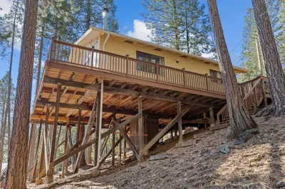 a tree house in the woods with a wrap around deck at Big Trees, Little Cabin in Arnold