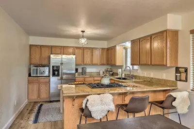 a kitchen with wooden cabinets and a kitchen island with chairs at Near Hiking and Wineries Arnold Cabin with Deck! in Arnold