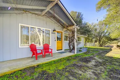 two red chairs sitting on the porch of a house at Dog-Friendly Oakhurst Home Walk to Downtown! in Oakhurst