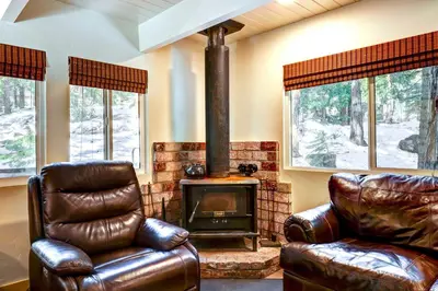 a living room with two leather chairs and a wood stove at Hike, Fish and Explore California Cabin with Deck! in Long Barn