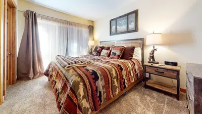 a bedroom with a bed and a table with a lamp at Mammoth Estates #140 condo in Mammoth Lakes
