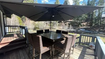 a black table with chairs and an umbrella on a deck at Creek Side Summit home in Stateline