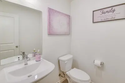 a bathroom with a sink and a toilet and a mirror at Pool Table and Patio! Spacious Merced Getaway in Merced