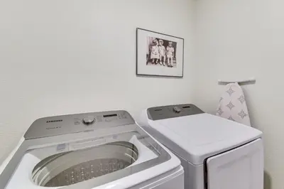 a laundry room with a washing machine and a picture at Pool Table and Patio! Spacious Merced Getaway in Merced