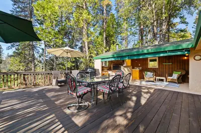 a deck with a table and chairs and an umbrella at Twain Harte Cabin in Town & Lake access in Twain Harte
