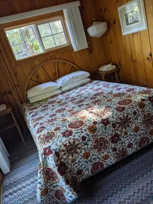 a bedroom with a bed with a floral bedspread and two windows at Cabin #3 in Strawberry