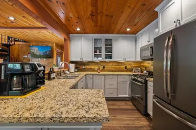 a large kitchen with white cabinets and stainless steel appliances at Cabin #4 in Strawberry