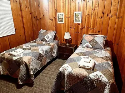 two beds in a room with wooden walls at Cabin #2 in Strawberry