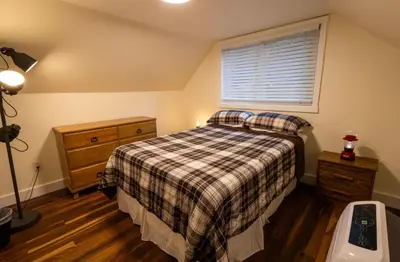 a bedroom with a bed with a plaid blanket and a window at Cabin #6 in Strawberry