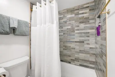 a bathroom with a white shower curtain and a brick wall at Heavenly Lakeside Retreat Close to downtown in South Lake Tahoe