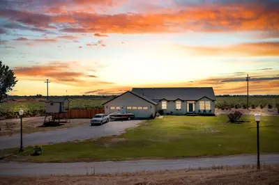 a house with cars parked in a yard with a sunset at Luxe & Comfy Vineyard Estate ~ Breathtaking Views! in Clarksburg