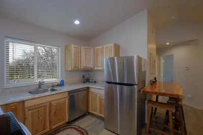 a kitchen with a stainless steel refrigerator and wooden cabinets at Bear Paw Cabin new construction near Yosemite in Mariposa