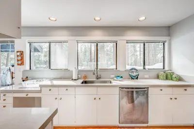 a kitchen with white cabinets and a sink and windows at Championship Pines in Incline Village