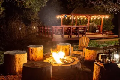 a fire pit in a yard with a gazebo at night at Forest Cabin by China Creek in Oakhurst