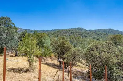 a fence in the middle of a field with trees at Cherry Cottage 15 min from Yosemite South Entrance in Oakhurst