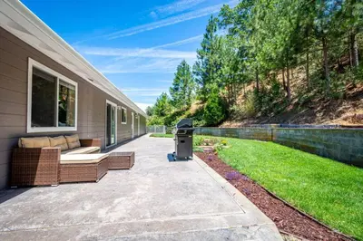 a patio with two couches and a grill next to a house at Alpine 4 Bedroom Retreat with Hot tub and Pool table in Coarsegold