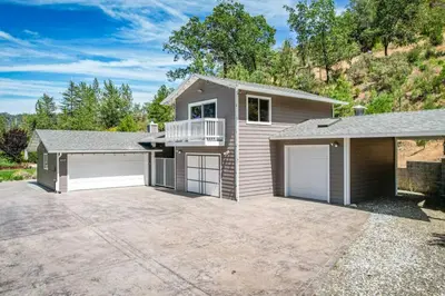 a house with two garage doors and a driveway at Alpine 4 Bedroom Retreat with Hot tub and Pool table in Coarsegold