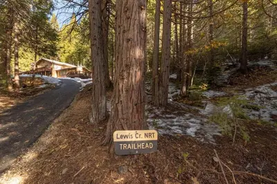 a sign on a tree next to a road at Sugarpine Trailhead Lodge at Lewis Creek Upper Trailhead just 7 miles from Yosemite in Oakhurst