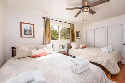 two beds in a room with a ceiling fan at Buckeye Bungalow w hot tub/firepit/views Pet Friendly in Oakhurst
