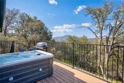 a hot tub on a deck with a view at Buckeye Bungalow w hot tub/firepit/views Pet Friendly in Oakhurst
