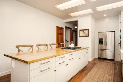a kitchen with white cabinets and a wooden counter top at Yosemite Country House sleeps 20 w/ hot tub, firepit, bonus studio in Oakhurst