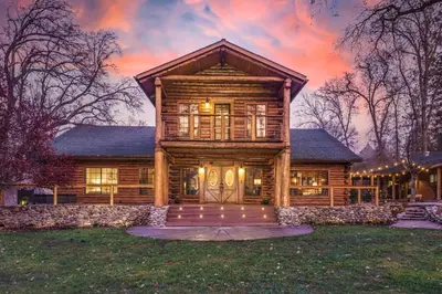 a large wooden house with a large front door at Log Cabin sleeps 20 with hot tub, EV Charger, firepit in Ahwahnee