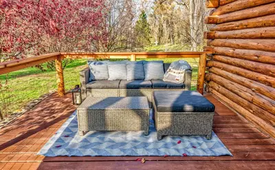 a patio with a couch and chairs on a wooden deck at Log Cabin sleeps 20 with hot tub, EV Charger, firepit in Ahwahnee